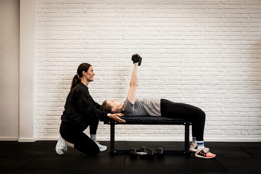 Nastasja guider en klient i dumbbell press på bænk